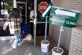 Health department staff members enter the Andrews County Health Department measles clinic carrying doses of the measles, mumps and rubella vaccine, in Andrews, Texas. 