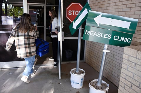 Health department staff members enter the Andrews County Health Department measles clinic carrying doses of the measles, mumps and rubella vaccine, in Andrews, Texas. 