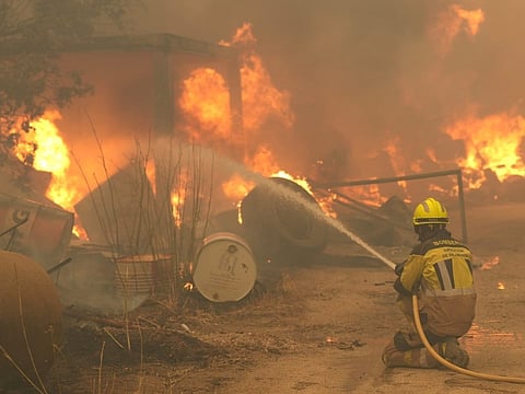 A firefighter waters burning tires and barrels while battling a wildfire in Cebreros area, near Avila, 80 kms west of Madrid on July 24, 2026.