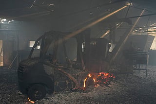 A picture taken on July 25, 2026 in El Tiemblo, 80 kms west of Madrid, shows burned machines, ashes and flames in 'Parquets Luz' wooden floor company, amid wildfires that have burned up to 25,000 hectares.