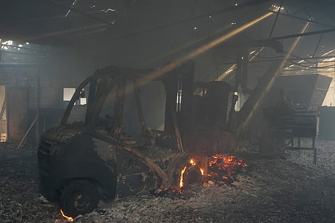 A picture taken on July 25, 2026 in El Tiemblo, 80 kms west of Madrid, shows burned machines, ashes and flames in 'Parquets Luz' wooden floor company, amid wildfires that have burned up to 25,000 hectares.