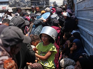 Displaced Palestinians line up to receive donated food at a community kitchen in Khan Younis, southern Gaza Strip, Thursday, July 23, 2026. 