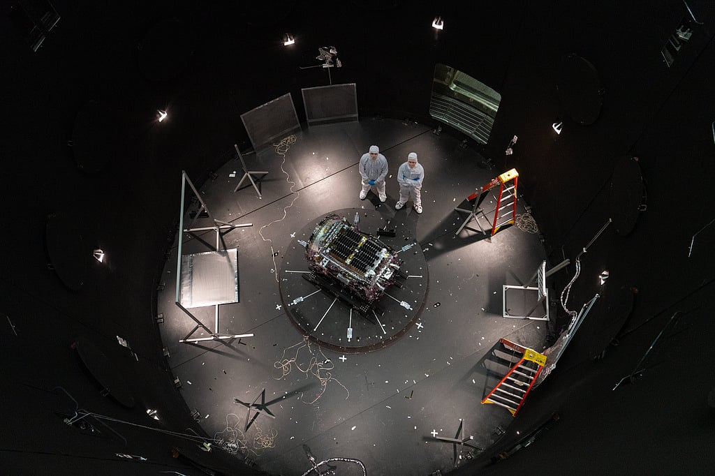 FILE - This photo provided by NASA shows Kieran Wilson, LINK's principal investigator, and Hunter Robertson, a space systems engineer, both at Katalyst Space, standing next to their spacecraft inside the SES (Space Environment Simulator) at NASA's Goddard Space Flight Center in Greenbelt, Md., April 17, 2026, ahead of thermal vacuum testing. (Sophia Roberts/NASA via AP, File)