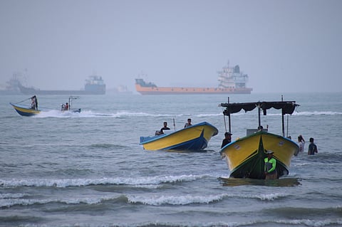 Small boats line the shore as cargo ships and other commercial vessels appear anchored in the Strait of Hormuz off Bandar Abbas, Iran.