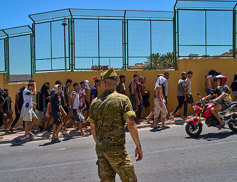 Migrants who crossed into Spain are escorted by Spanish soldiers toward the Spanish-Moroccan border for their return to Morocco from the Spanish enclave of Ceuta.