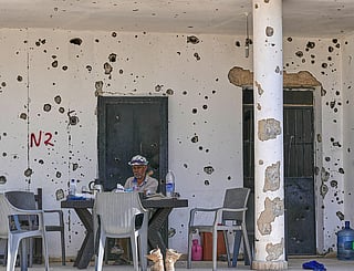 A Lebanese man sits outside his damaged house in the village of Zawtar al-Gharbieh, south Lebanon.