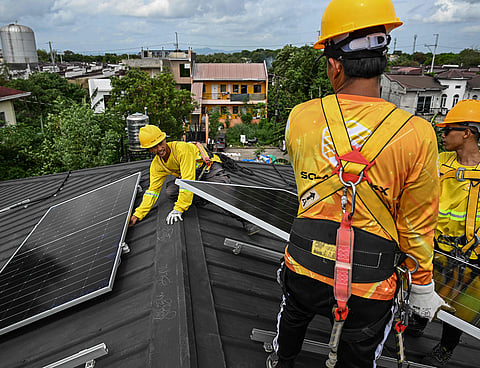 Workers installing solar panels on a roof in Carmona, in the Philippine province of Cavite.