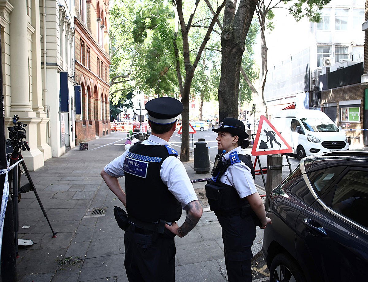 Police officers stand beside cordon tape at Endell road in covent garden, central London.