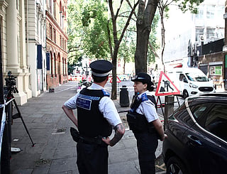 Police officers stand beside cordon tape at Endell road in covent garden, central London.
