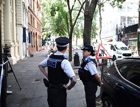 Police officers stand beside cordon tape at Endell road in covent garden, central London.
