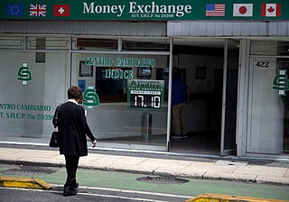 A woman walks past a currency exchange office displaying an exchange rates in Mexico City on August 14, 2026.