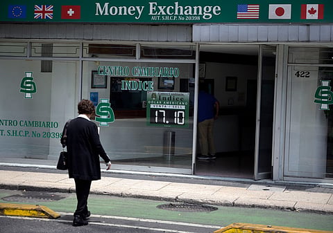 A woman walks past a currency exchange office displaying an exchange rates in Mexico City on August 14, 2026.