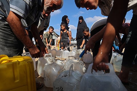 Displaced Palestinians gather to fetch water from a cistern at a shelter camp in Bureij, central Gaza Strip on August 24, 2026.