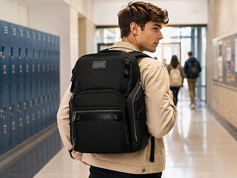 Student carrying a Black Tumi Alpha backpack through a school hallway