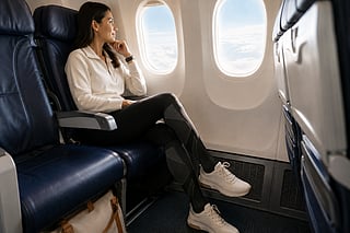 A passenger wearing compression socks while seated on a long flight