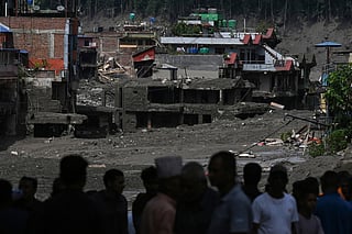 Residents look at buildings submerged by mud following flash floods and a landslide disaster in Trishuli Bazar, in Nepal's Nuwakot district on August 26, 2026.