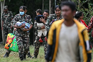 Army personnel carry rescued children in the aftermath of flash floods at Trishuli camp in Nepal's Nuwakot district on August 29, 2026.