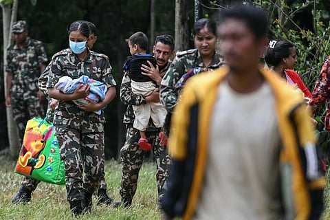 Army personnel carry rescued children in the aftermath of flash floods at Trishuli camp in Nepal's Nuwakot district on August 29, 2026.