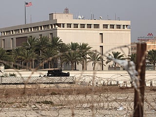 A Bahraini armored personnel vehicle and personnel reinforce US Embassy security just outside of a gate to the building, surrounded in barbed wire, in Manama, Bahrain.