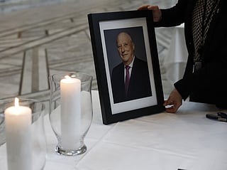 A staff member sets up a table displaying a portrait of the late King Harald V of Norway inside Oslo City Hall in Oslo on August 29, 2026, for members of the public wishing to sign condolence books following his passing.