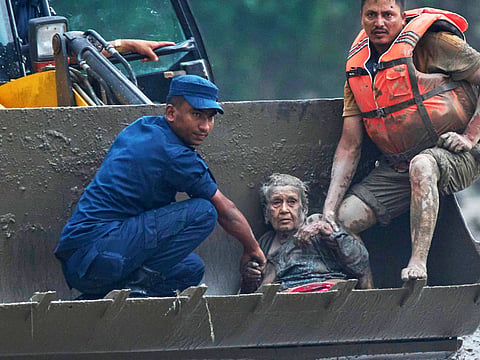 Rescuers use an earthmover to carry 97-year-old Guna Maya Bohara to safety after she was rescued from beneath rubble following flash floods along the Trishuli River in Nepal’s Nuwakot district