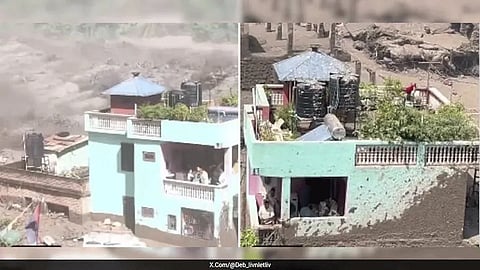 Still standing: A mint-green home withstands the torrent in Nuwakot as mud, water and debris sweep through the surrounding area. The family inside survived.