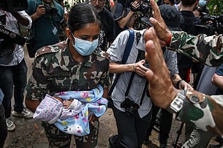 An Army personnel carries a rescued infant in the aftermath of flash floods at Trishuli camp in Nepal.