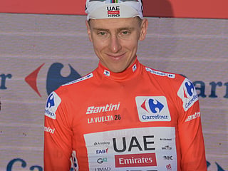 Slovenia's Tadej Pogacar, wearing the overall leader's red jersey celebrates on the podium after the second stage of the La Vuelta cycling race, with start in Monaco and finish in Manosque, France, Sunday, Aug. 23, 2026.  