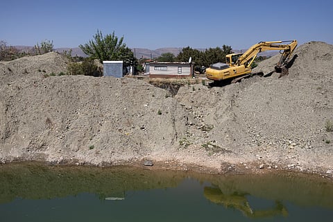 A residence overlooks an open pit dug by illegal miners using an excavator searching for chrome in Bapong, a mining village in North West province, on August 25, 2026.