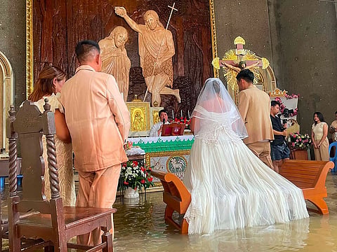 Couple Leian Lieza Galang and Gilbert Chico facing the altar during their wedding ceremony in a flooded church in Hagonoy town.