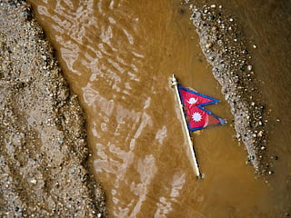 A Nepal flag lies on a muddy track near the banks of the Trishuli river in Dhading District, Nepal, Sunday, Aug. 30, 2026. (AP Photo/Niranjan Shrestha)