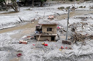 This aerial photograph shows Om Bahadur (C), sitting on the ledge of his damaged house, a week after the devastating flash floods at Baireni in Nepal's Dhading district on September 2, 2026.