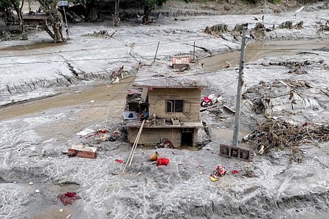 This aerial photograph shows Om Bahadur (C), sitting on the ledge of his damaged house, a week after the devastating flash floods at Baireni in Nepal's Dhading district on September 2, 2026.