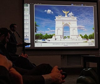 An image of President Donald Trump's proposed triumphal arch to commemorate the country's 250th anniversary is displayed during a public meeting of the Commission of Fine Arts at the National Building Museum on April 16, 2026 in Washington, DC. The Commission of Fine Arts voted unanimously to move forward with a proposed 250-foot arch informally dubbed the "Arc de Trump" that would sit in a roundabout near Memorial Bridge on the Arlington, Virginia side of the Potomac River between Arlington Cemetery and the Lincoln Memorial.