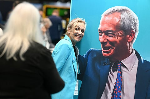 A delegate poses for a photo with an image of Nigel Farage on the second day of the annual Reform UK party conference at the NEC in Birmingham, central England on September 4, 2026.