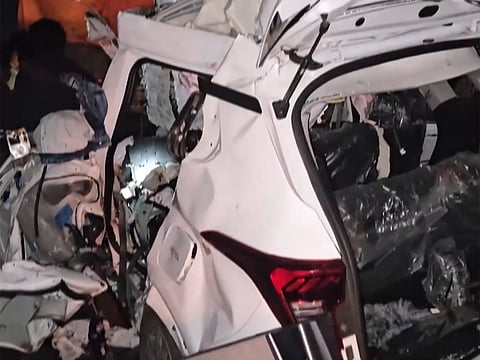 Car badly mangled after hitting stationary lorry near highway construction work.
