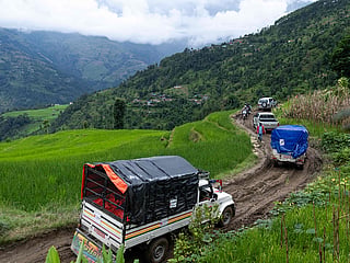 Vehicles carrying food and other essentials make their way through a damaged muddy road leading to Rasuwa in the aftermath of flash floods in Nepal's Nuwakot district on September 4, 2026.