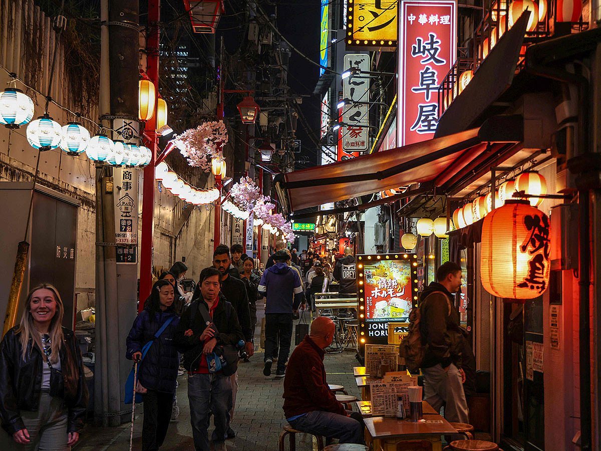 People walk past izakaya restaurants in the Shinjuku district in Tokyo.