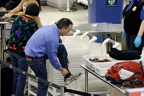 An airline passenger pulls off his shoes to be scanned as he prepares to go through a security checkpoint at Seattle-Tacoma International Airport, Jan. 4, 2010, in SeaTac, Washington.