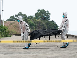 Philippine coast Guard personnel in protective suit carry a body bag of a victim from the ferry fire blaze to a tent for identification at the port of Borac in Coron, Palawan province on September 12, 2026.