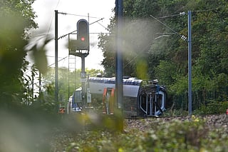SNCF workers stand next to a derailed train carriage in Cléon, northwestern France, on September 12, 2026, the morning after the train derailed.