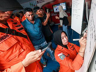 Relatives of affected passengers look on as a National Search and Rescue Agency (Basarnas) officer writes updates on a whiteboard amid ongoing rescue operations on the stricken Virgo Transport 8 ferry, at Trisakti Bandarmasih Port in Banjarmasin, South Kalimantan.