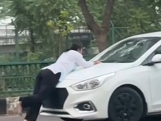 Footage shows the woman clinging to the front of a white car as it continues moving.