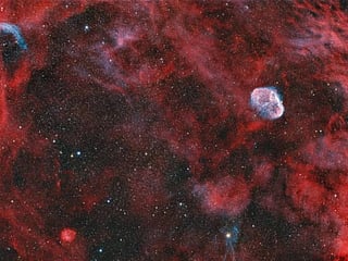 The smaller telescope produced a wide-field image showing the Crescent Nebula surrounded by a dense region of stars and gas. 
