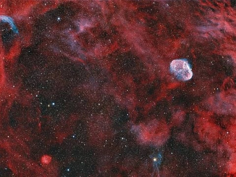 The smaller telescope produced a wide-field image showing the Crescent Nebula surrounded by a dense region of stars and gas. 