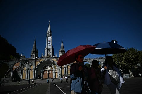 People walk in front of the Basilique Notre-Dame du Rosaire five days ahead of a visit by Pope Leo XIV to the site as part of his apostolic trip to France, in Lourdes on September 22, 2026.