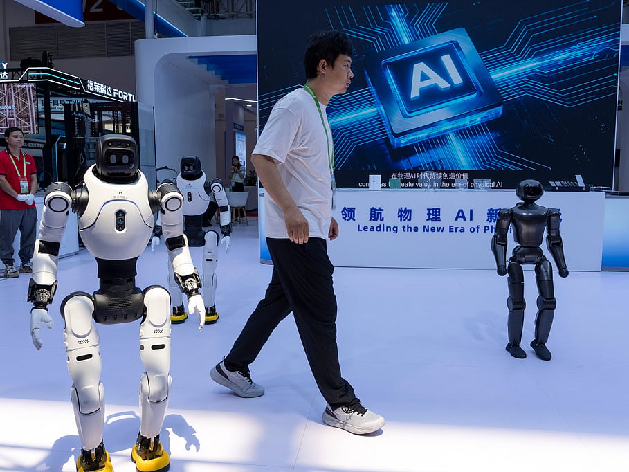 FILE- A worker passes by robots from Chinese company Lens at the China International Supply Chain Expo in Beijing on Monday, June 22, 2026. (AP Photo/Ng Han Guan, File)
