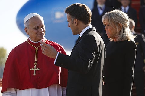 Pope Leo XIV (L) is welcomed by France's President Emmanuel Macron (C) and his wife Brigitte Macron (R) on the tarmac after disembarking from the plane upon his arrival at the Orly airport, in the outskirts of Paris, on September 25, 2026 for his four days visit to France.