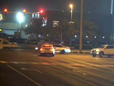 Sharjah Police camera captures a driver running a red light at night.