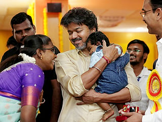Tamil Nadu CM C. Joseph Vijay holding a child during the launch of a scheme offering newborns in public health facilities with a one-gram gold ring, at the Government Rajaji Hospital in Madurai. 